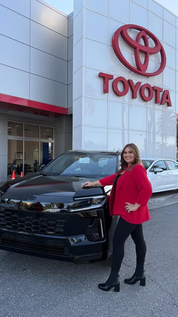 Camila ao lado de uma Toyota RAV4 2026 preta na concessionária Toyota